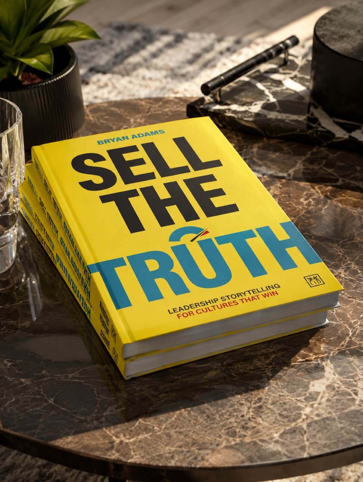 Sell The Truth by Bryan Adams — hardback book with bright yellow cover, on a marble table